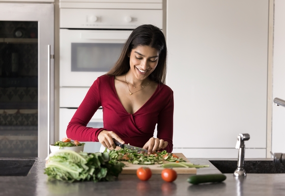 young person preparing a salad with tomatoes and lettuce